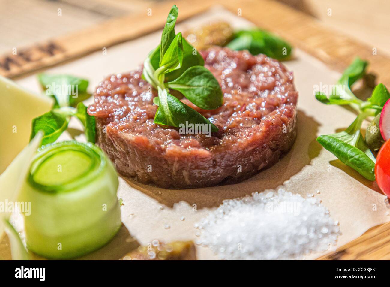 Tartare - un antipasto tradizionale di manzo crudo con spezie si trova su una tavola di legno nel ristorante. Foto Stock