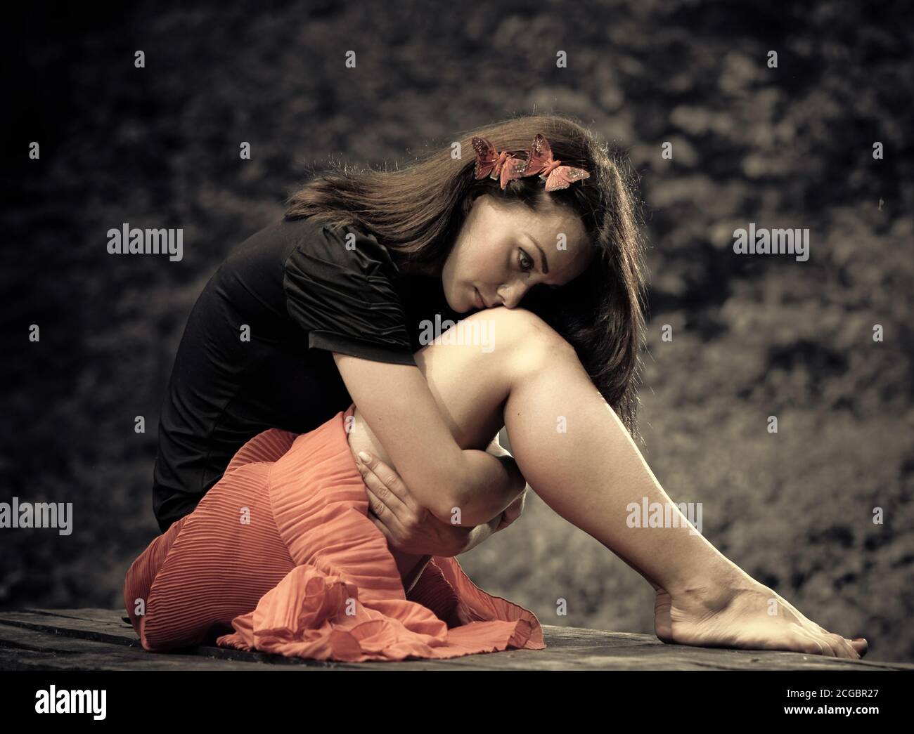 Giovane donna di brunetto seduta all'aperto su una panca di legno Foto Stock