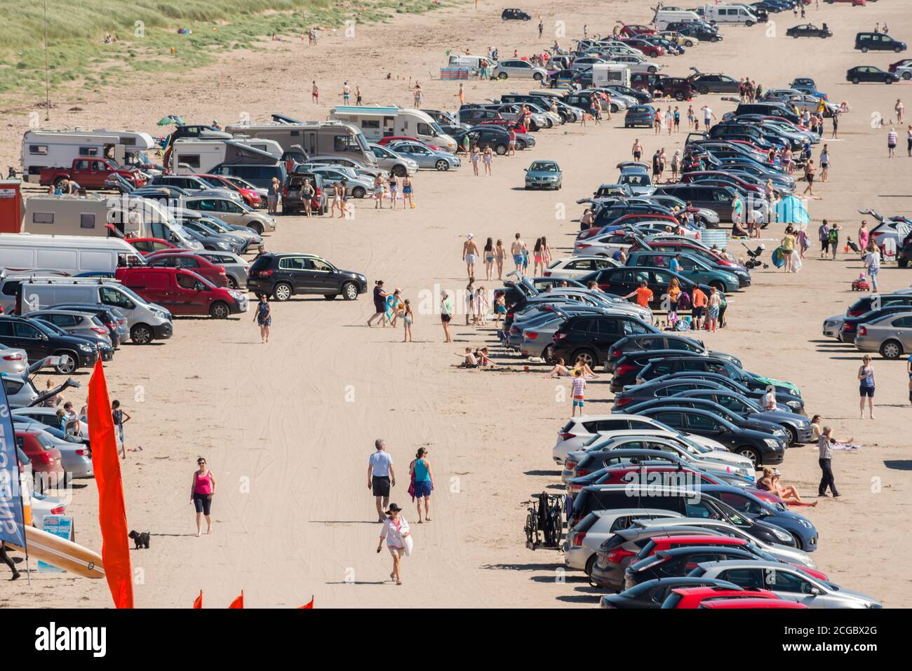 Ondata di caldo Irlanda clima soleggiato che si affaccia sui bagnanti gente sulla spiaggia sabbiosa e numerose auto sulla affollata Inch Beach, contea di Kerry, Irlanda Foto Stock