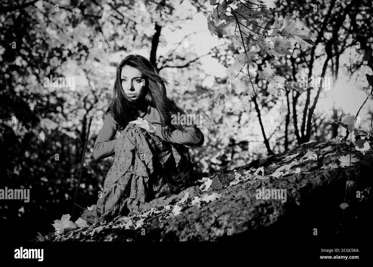 giovane donna in abito vintage su una pietra di foresta a. autunno stagione tramonto sfondo Foto Stock