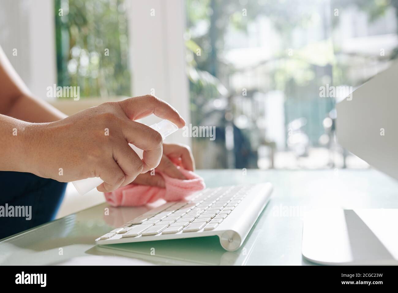 Lavoratore in ufficio spruzzando spray antibatterico sulla tastiera Foto Stock