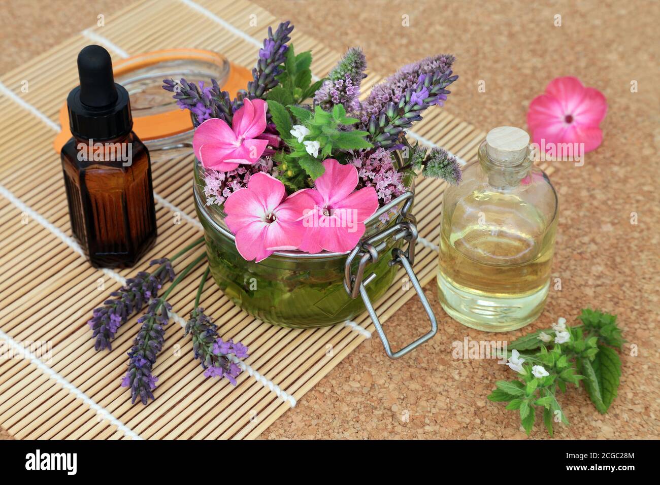 Medicina di erbe naturopatica con fiori estivi ed erbe sciolte e che si inzidiscono in un vaso con gli oli per fare l'olio essenziale di aromaterapia. Foto Stock
