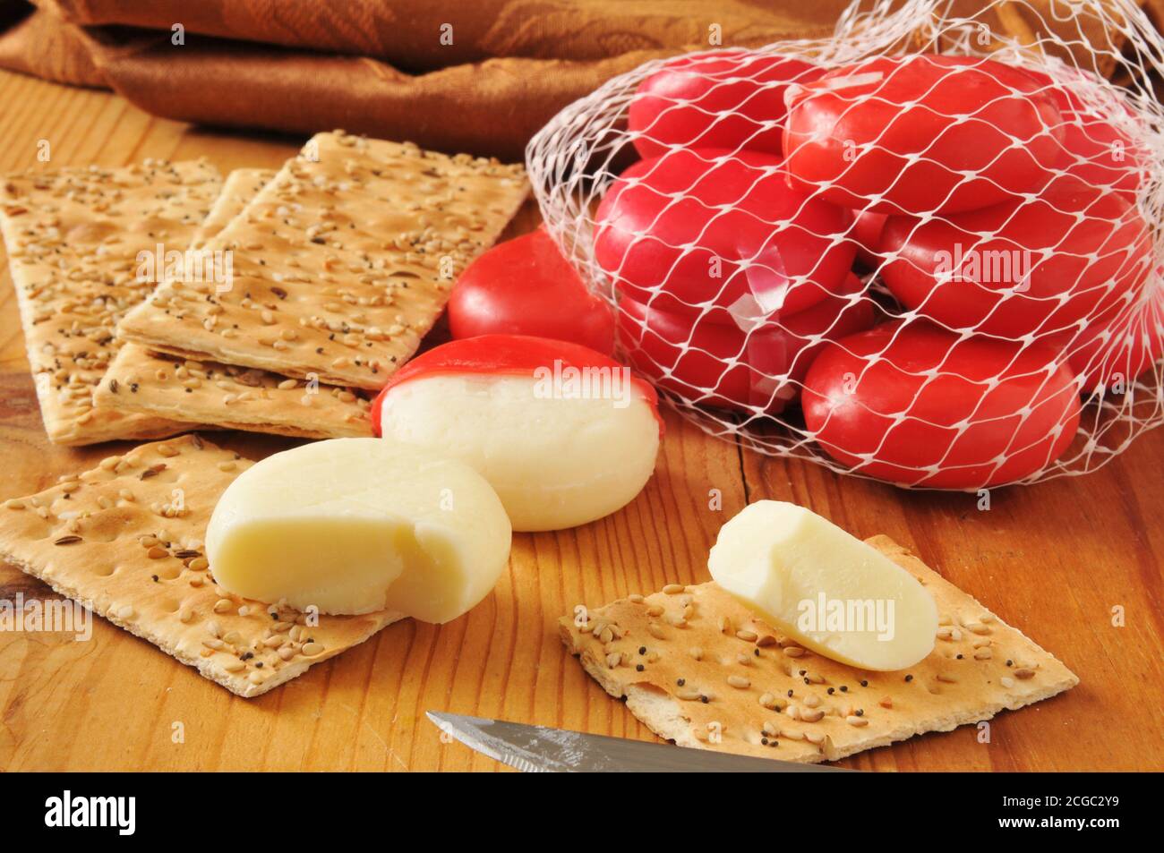 Mini pagnotte di formaggio cheddar bianco in involucri di cera rossa con cracker di pane piatto salati Foto Stock