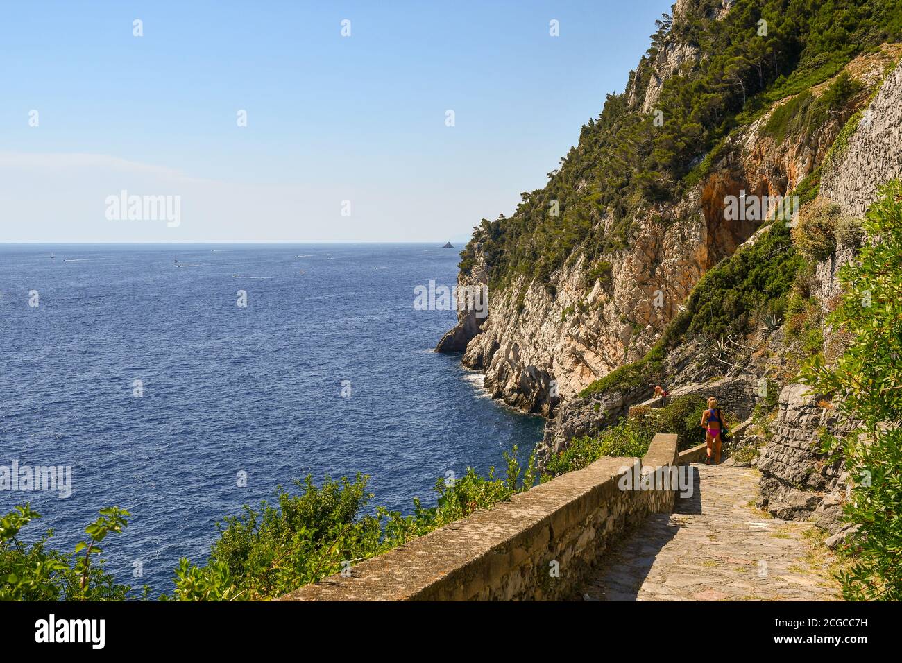 Vista panoramica dalla scogliera che domina il mare ligure con due turisti sul sentiero in pietra in estate, Porto Venere, la Spezia, Liguria, Italia Foto Stock
