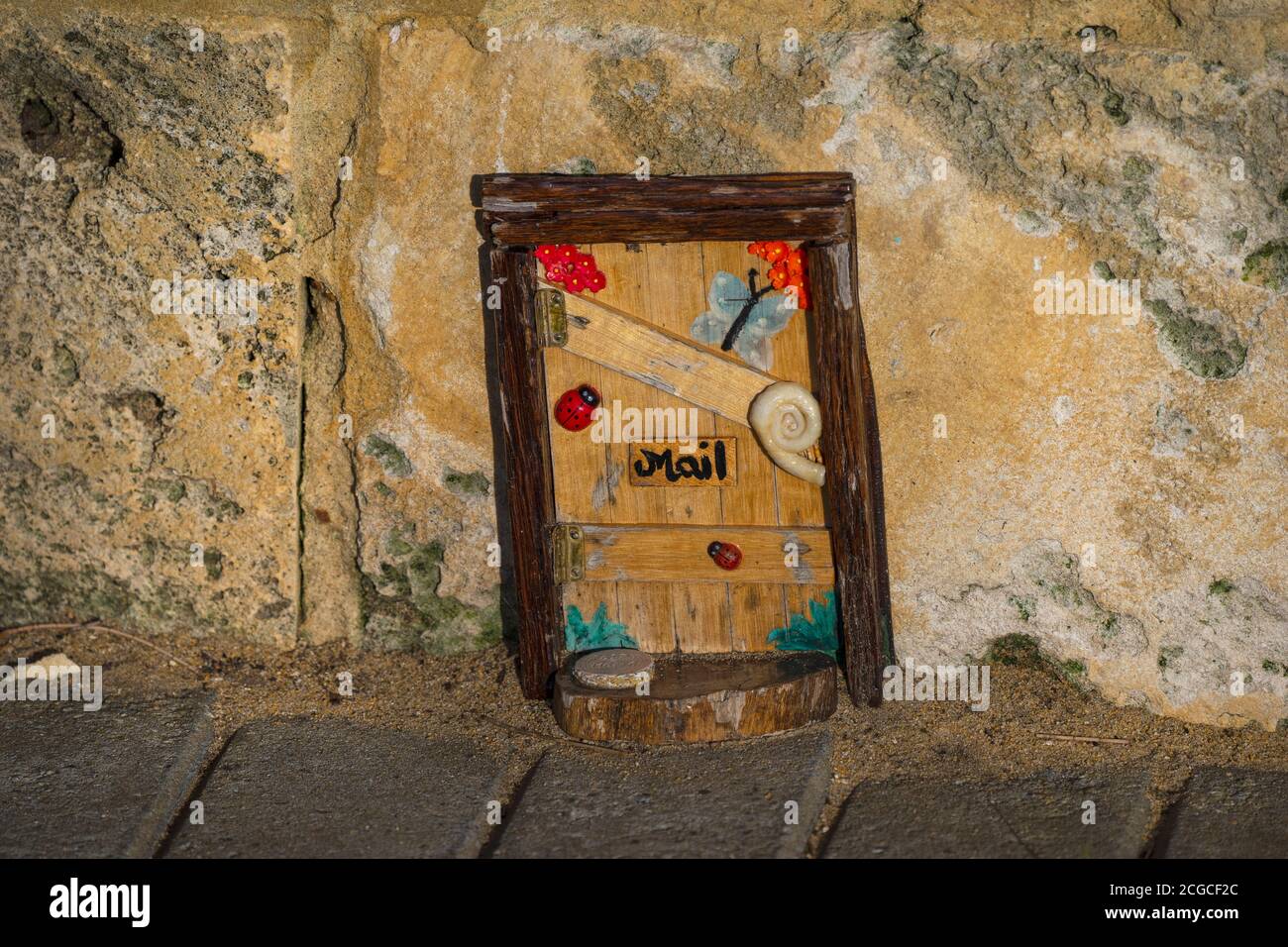 Mandurah, Australia Occidentale - Agosto, 2020: Installazione di una bella piccola porta in legno fatta a mano con decorazione e segno postale su una parete di pietra calcarea posteriore Foto Stock