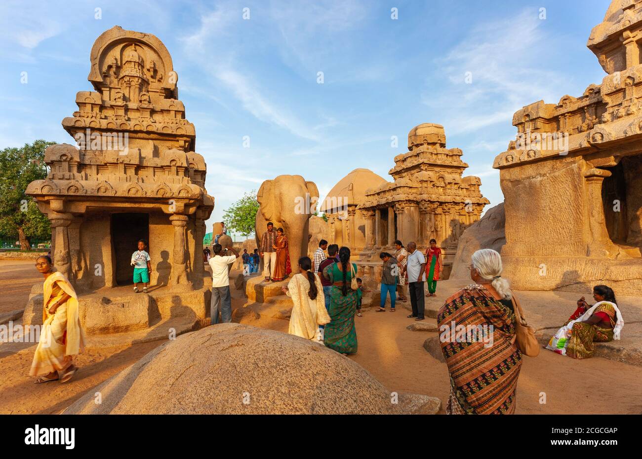 Turisti a indù religiosi rock-taglio monumenti e complesso tempio in una luminosa serata di sole a Mamallapuram, Tamil Nadu, India. Foto Stock