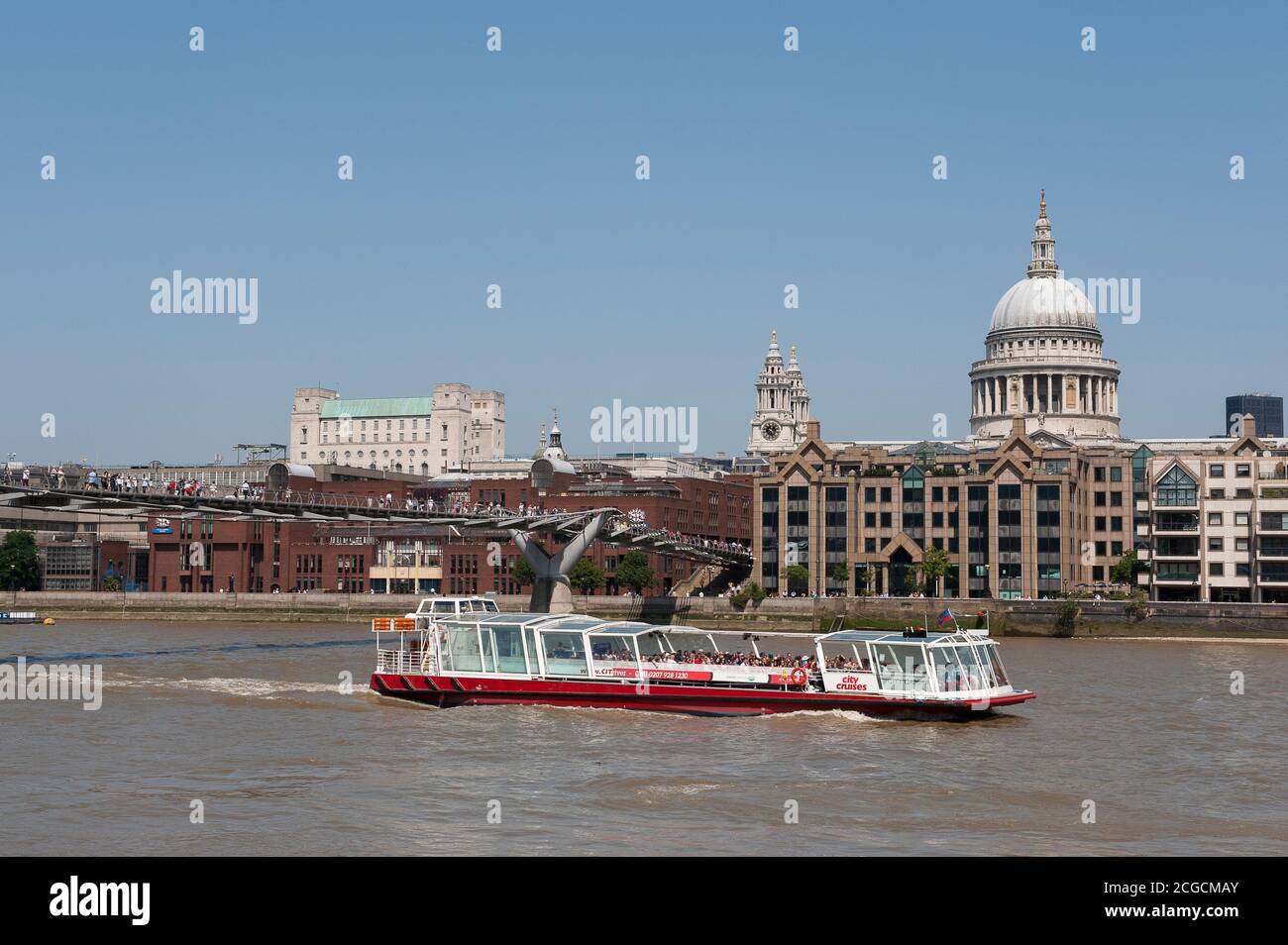 La città naviga in barca passando sotto il Millennium Bridge sul Tamigi con la cattedrale di St Paul sullo sfondo, City of London, Inghilterra. Foto Stock