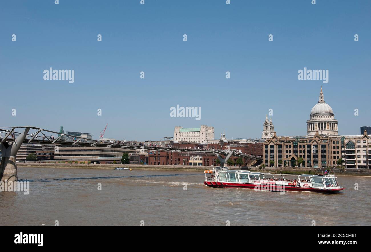 La città naviga in barca passando sotto il Millennium Bridge sul Tamigi con la cattedrale di St Paul sullo sfondo, City of London, Inghilterra. Foto Stock