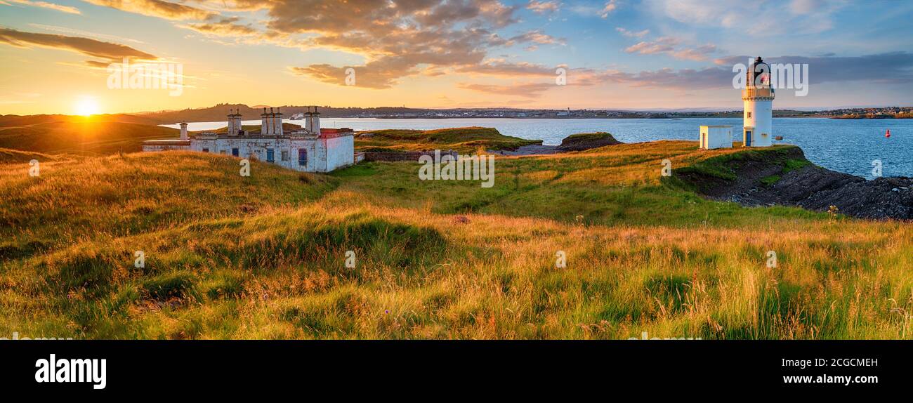 Vista panoramica del tramonto sul faro e sui cottage della guardia costiera A Arnish Point nel porto di Stornoway sull'Isola di Lewis in Scozia Foto Stock