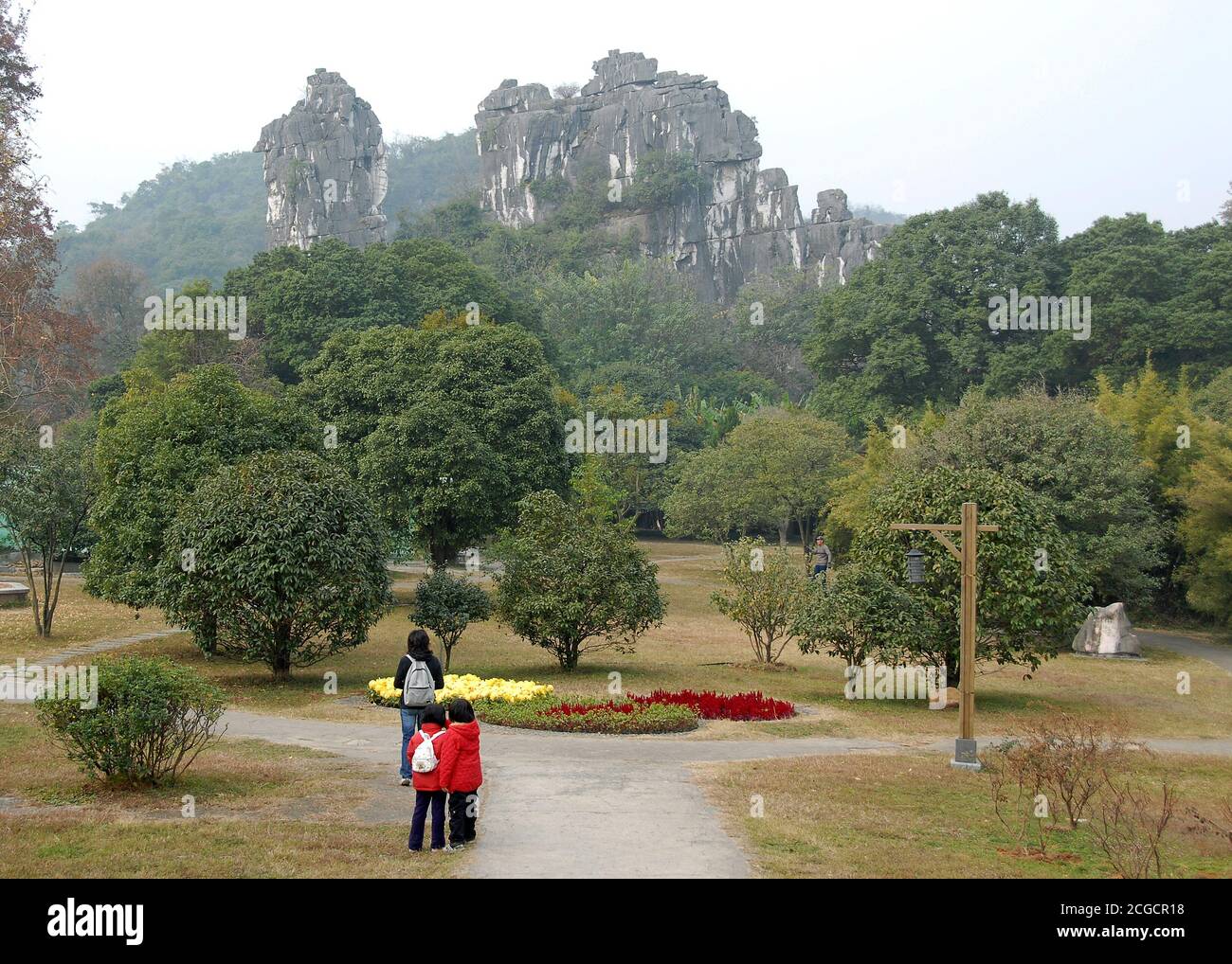 Persone che camminano nei giardini del Seven Star Park a Guilin nella provincia di Guangxi, Cina. Alle spalle si trova la famosa formazione carsica del Camel Hill. Foto Stock