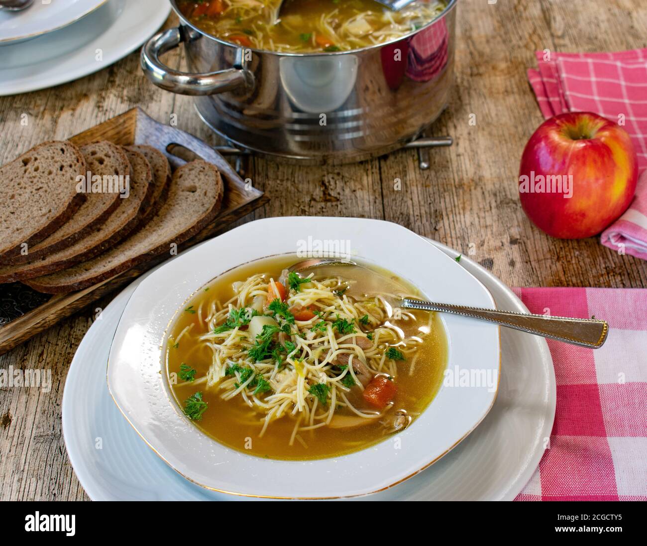 tavolo da pranzo con zuppa di pollo con piatto, cucchiaio, pentola Foto Stock