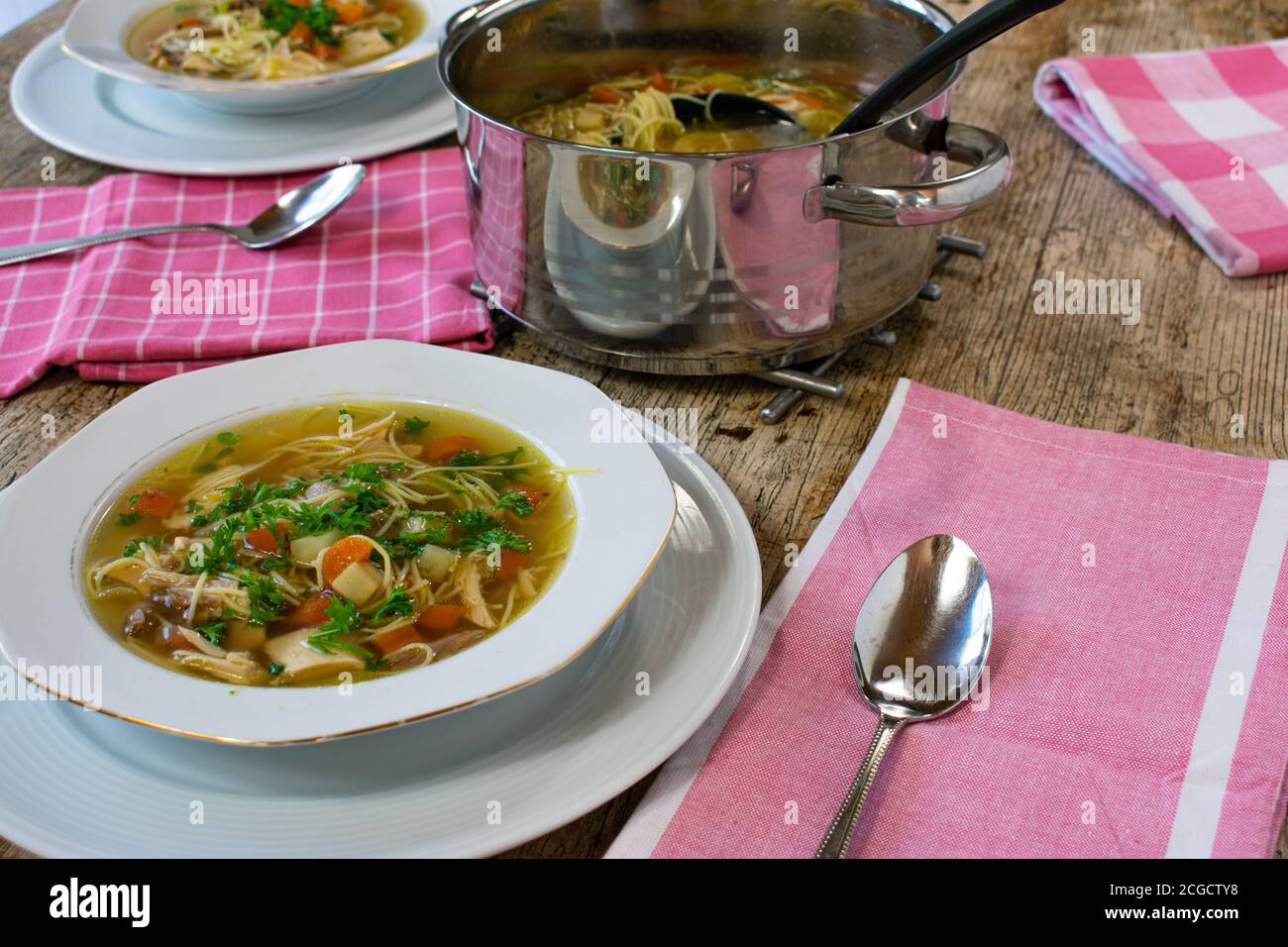 tavolo da pranzo con zuppa di pollo con piatto, cucchiaio, pentola Foto Stock