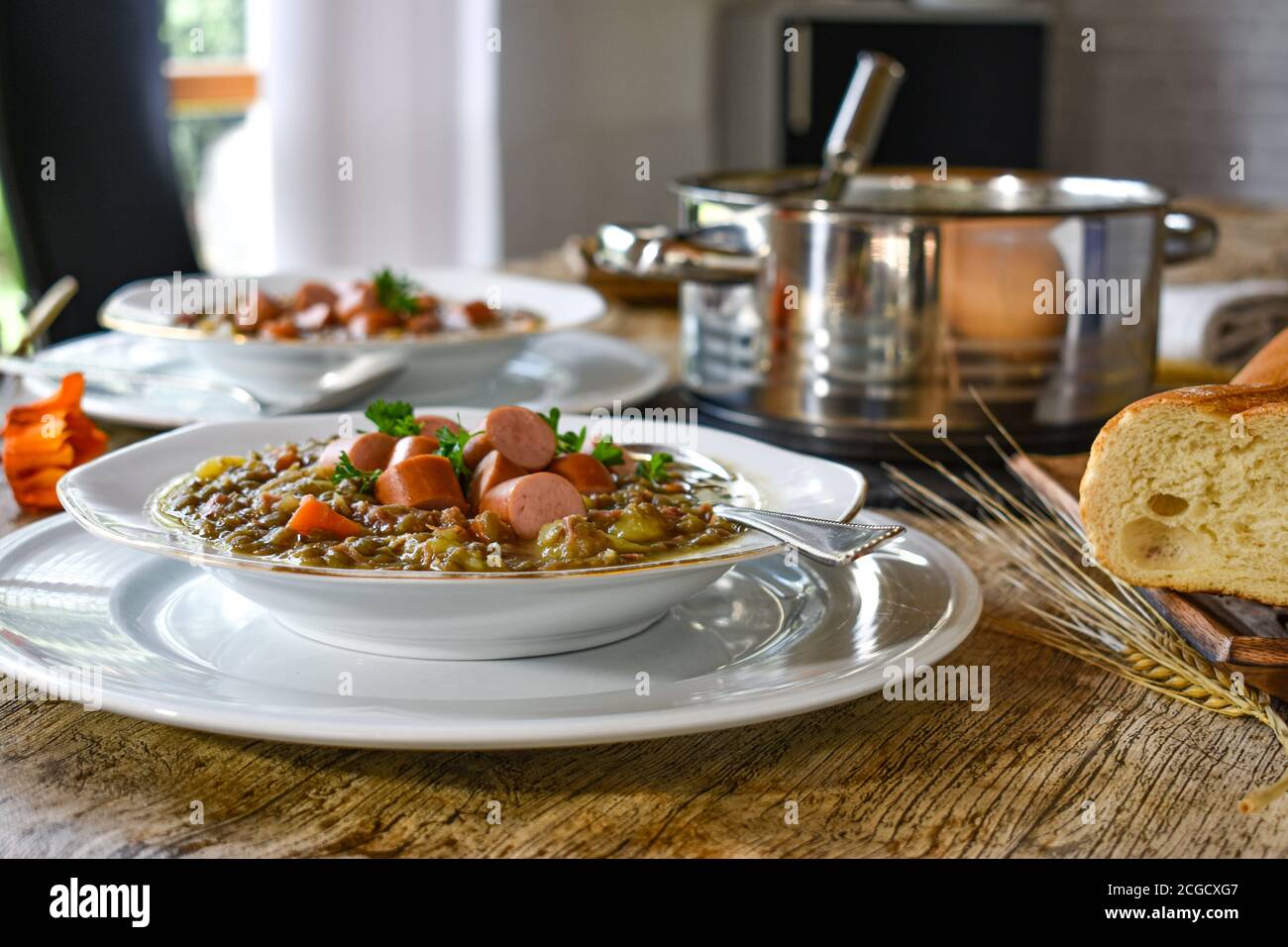 zuppa di lenticchie con hot dog su un piatto bianco servita su un tavolo con sfondo di legno Foto Stock