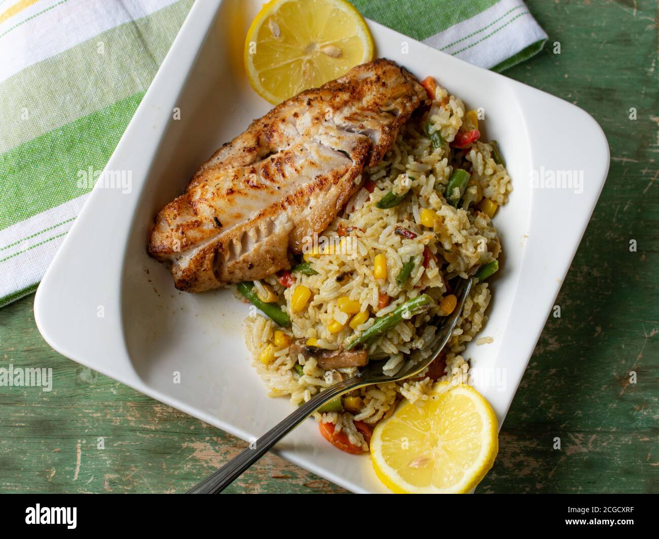 pesce fritto in padella naturale con riso e verdure marroni Foto Stock