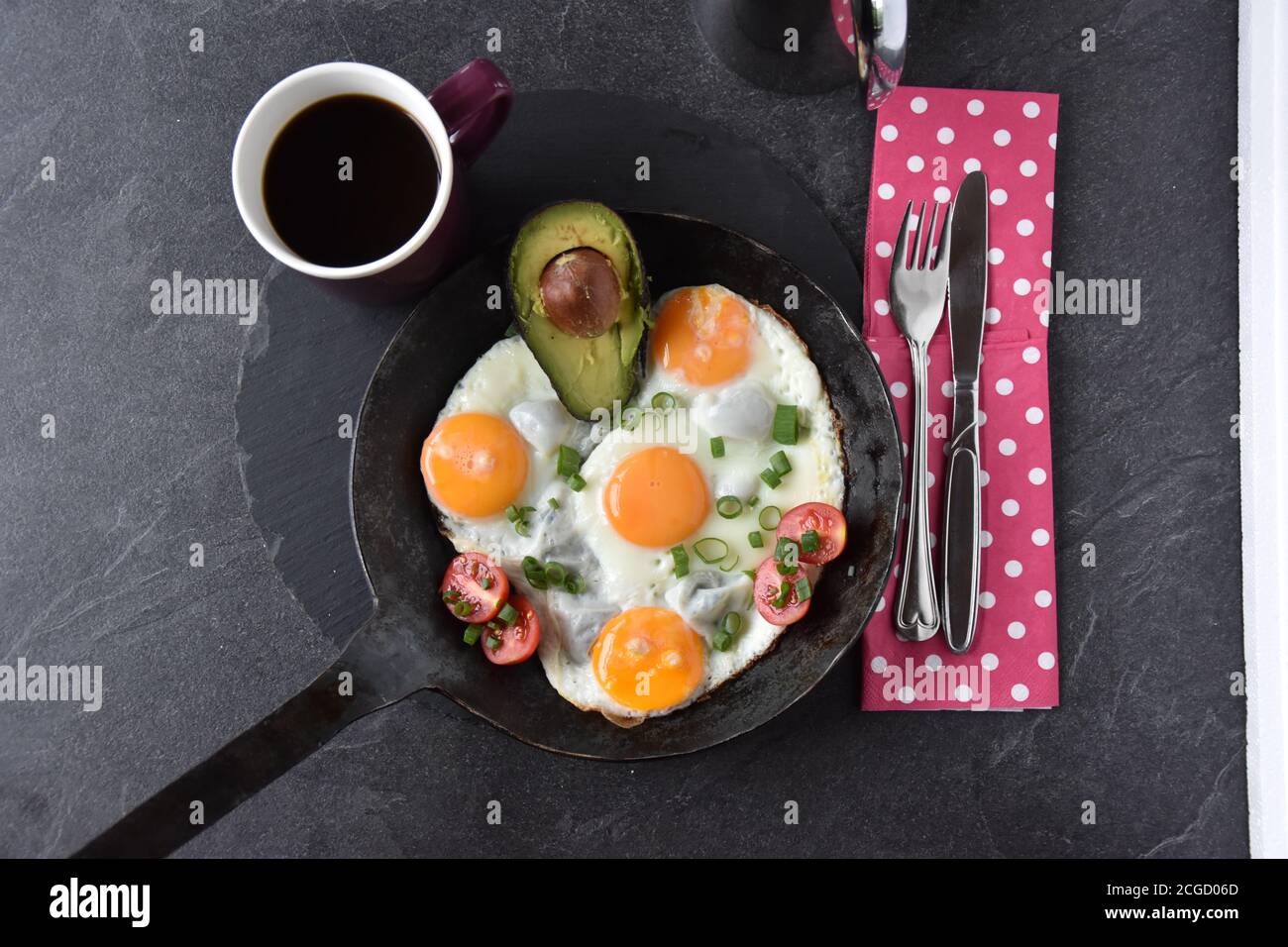 Uova fritte con il lato soleggiato in una padella con un Pezzo di avocado - colazione chetogena Foto Stock