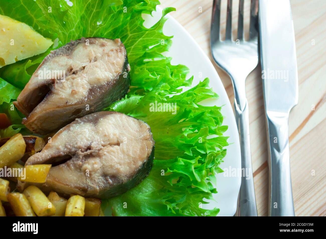 Pesce fritto con guarnitura vegetale con lattuga verde su un sfondo di legno Foto Stock
