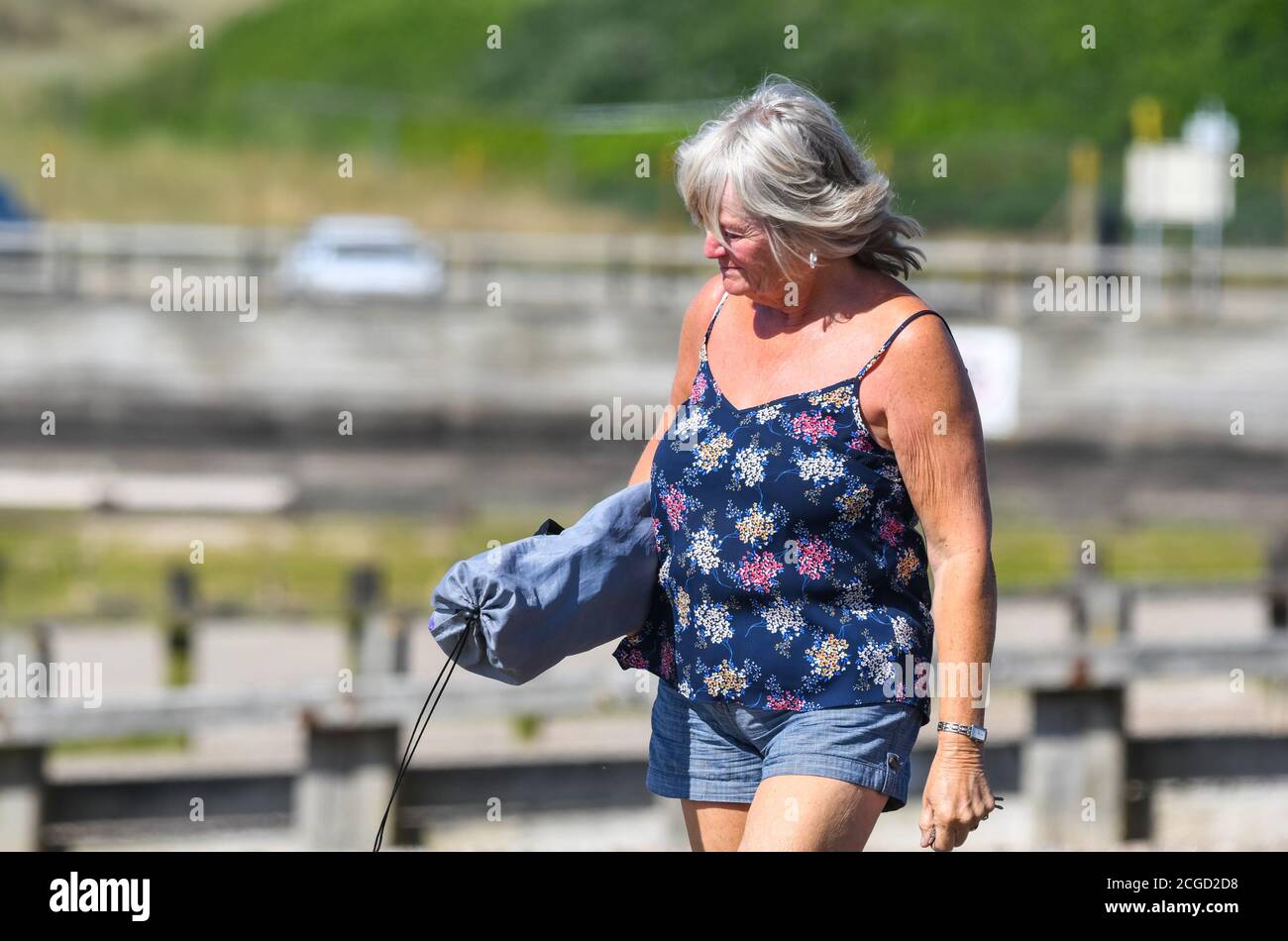 Donna di mezza età che si sveglia in estate, indossando abiti estivi, squinting dal sole luminoso, nel Regno Unito. Foto Stock
