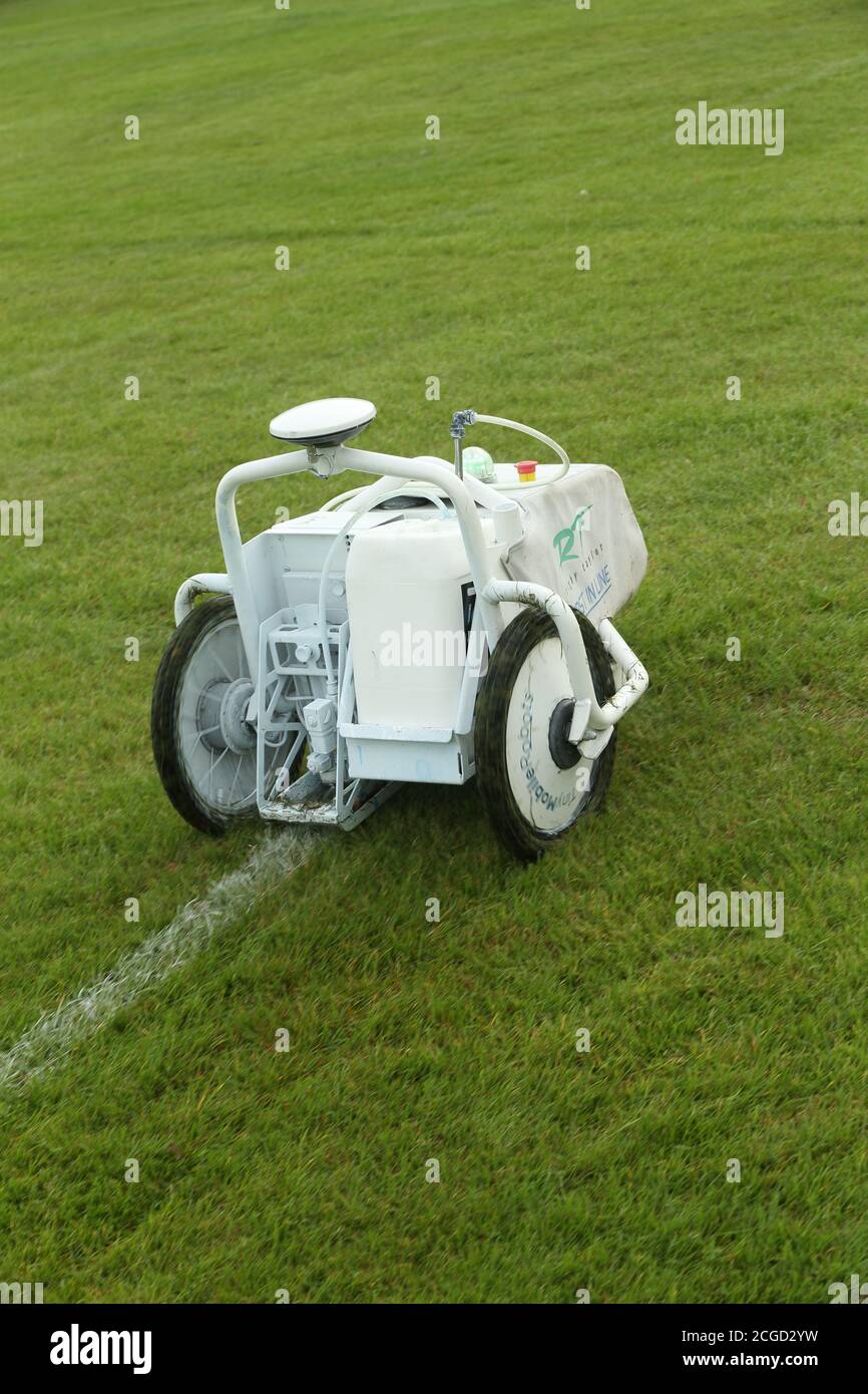 Macchina automatica robotica per la verniciatura di linee bianche che opera su erba in un campo sportivo Foto Stock