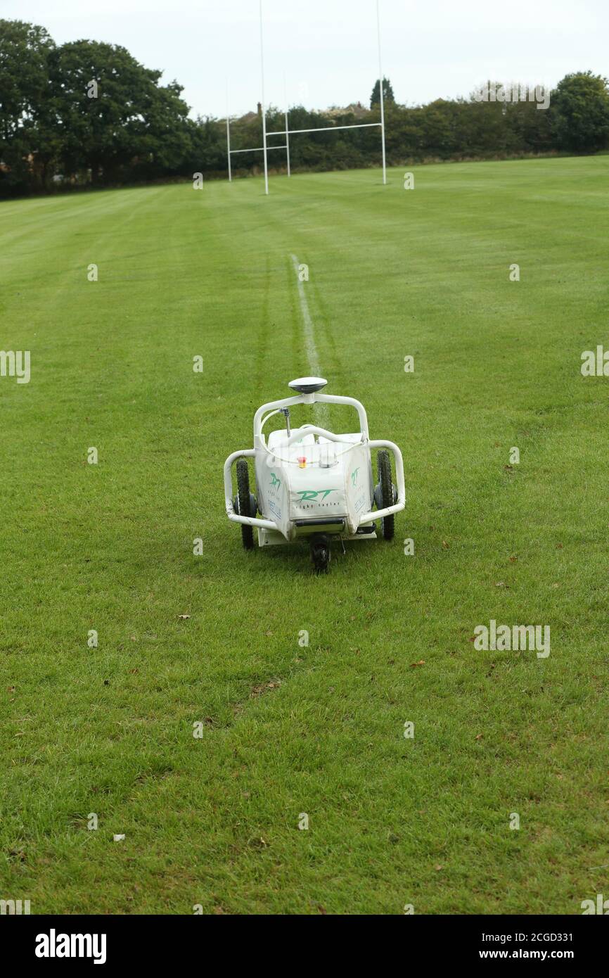 Macchina automatica robotica per la verniciatura di linee bianche che opera su erba in un campo sportivo Foto Stock