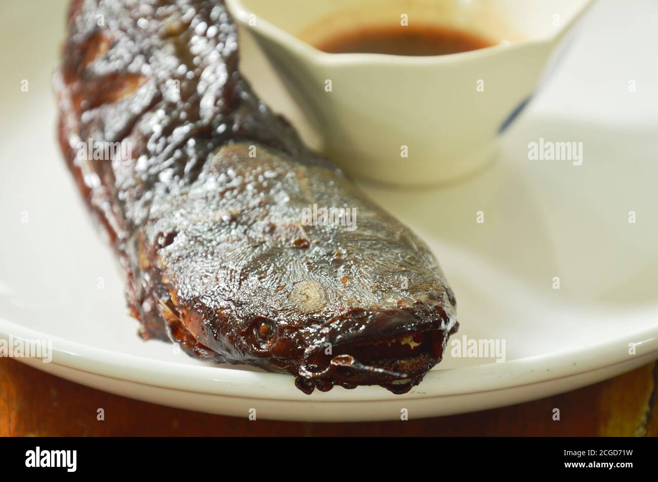 immersione di pesce gatto alla griglia con salsa piccante su piatto Foto Stock