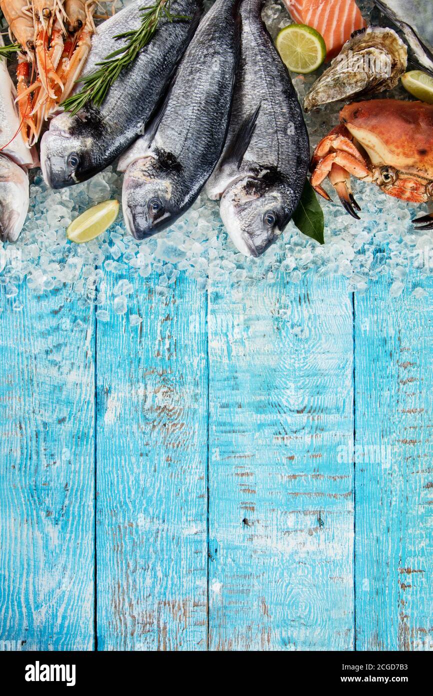 Pesce orata con frutti di mare, granchio, cozze, gamberi, pesce e altre conchiglie serviti su ghiaccio tritato e tavolo di legno Foto Stock