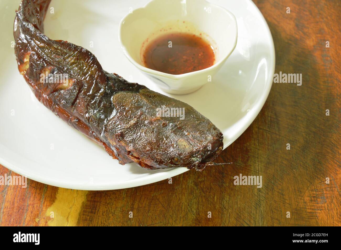 immersione di pesce gatto alla griglia con salsa piccante su piatto Foto Stock