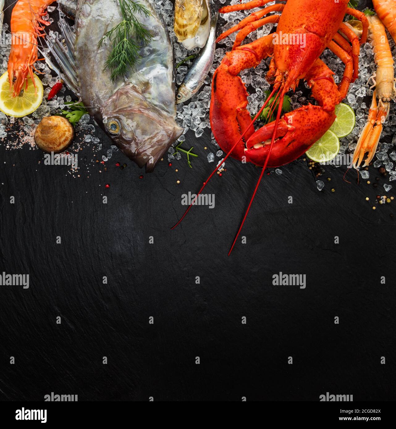Aragosta intera con frutti di mare, cozze, gamberi, pesce, bistecca, sardine e altre conchiglie servite su pietra nera Foto Stock