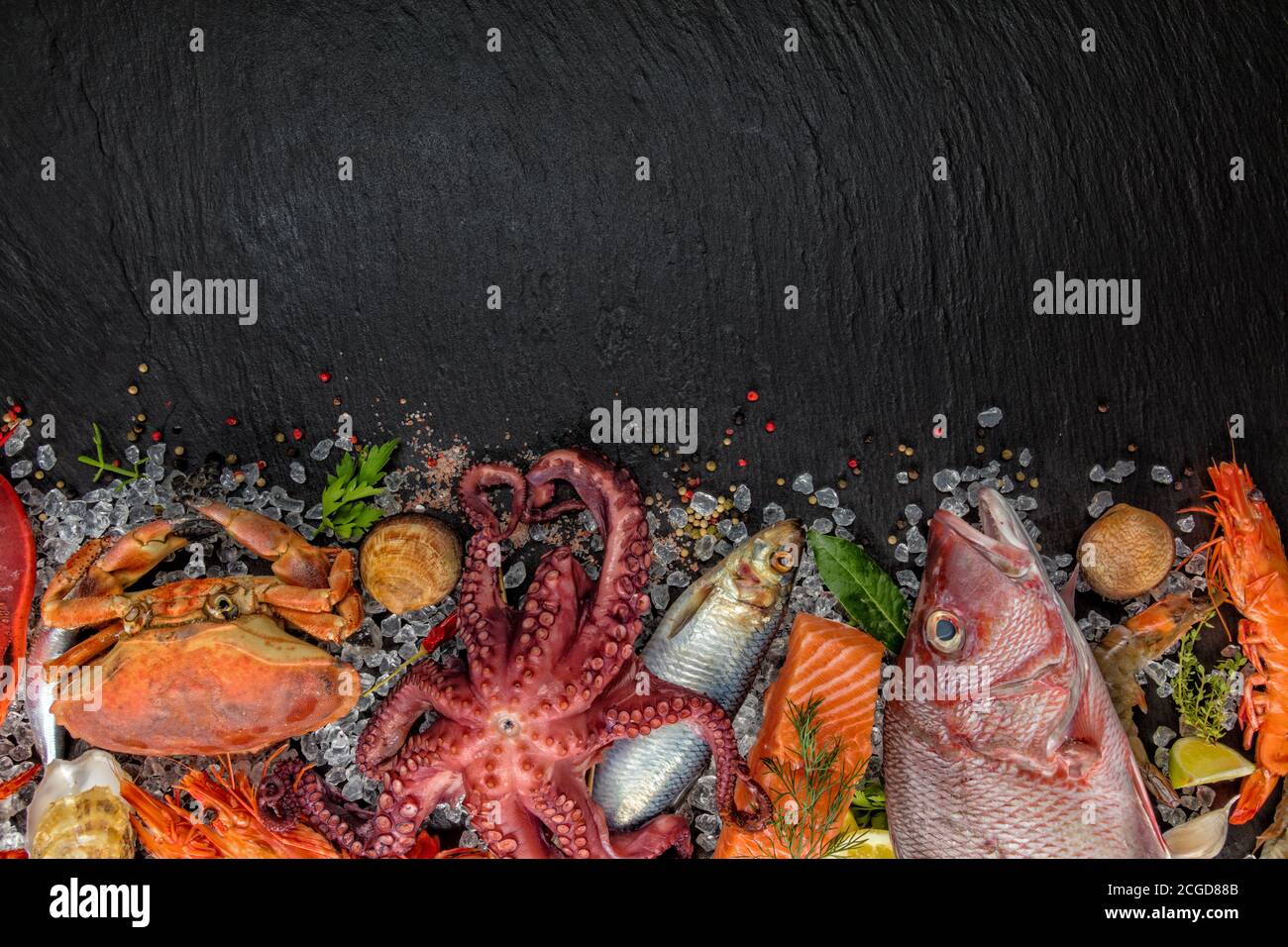 Aragosta intera con pesce, granchio, cozze, gamberi, pesce, bistecca di salmone, sgombro e altre conchiglie servite su pietra nera Foto Stock