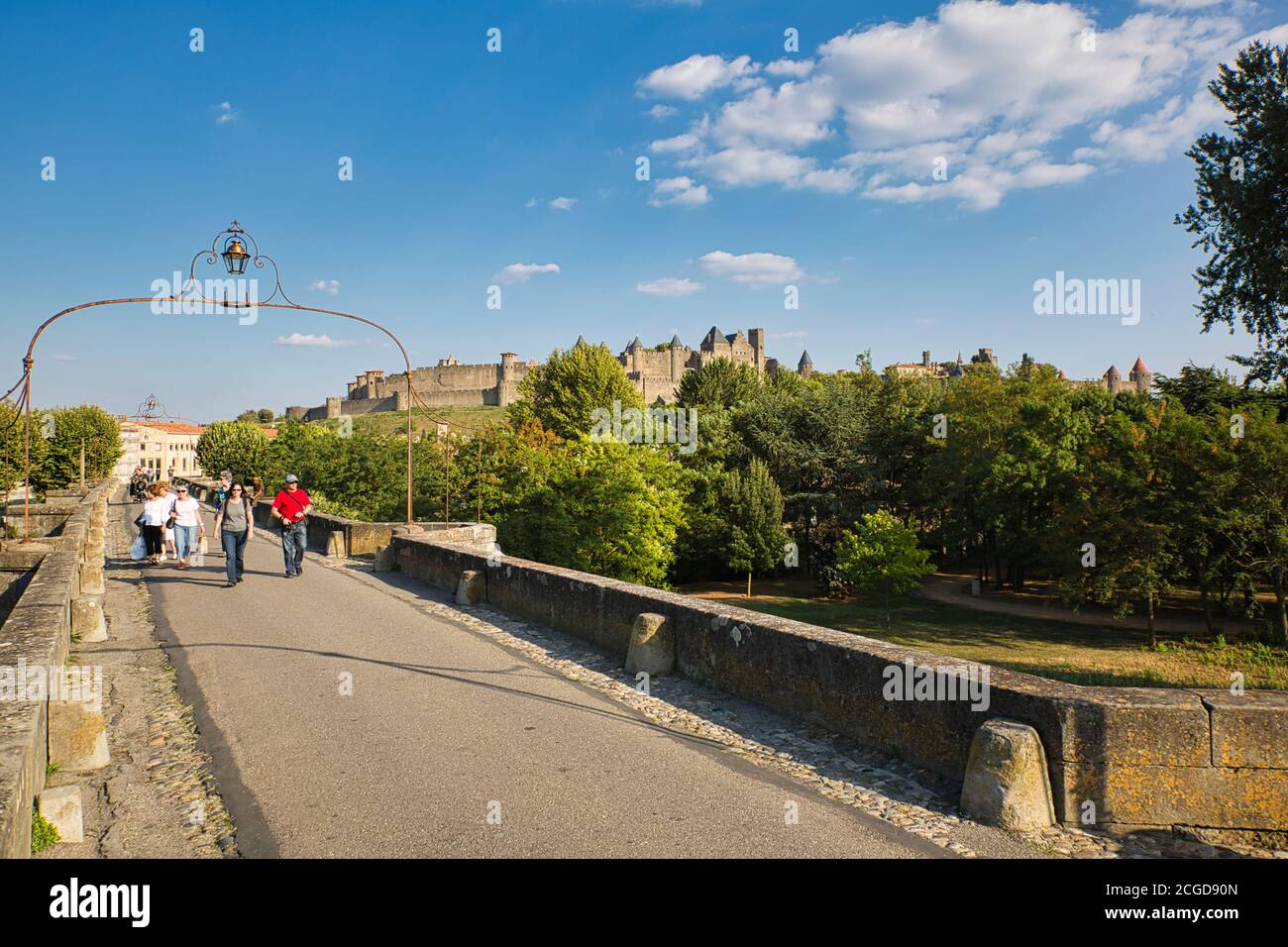 Vista a distanza del castello e merli a la Cité, Carcassonne, Languedoc-Roussillon, Francia, con persone che camminano in primo piano Foto Stock