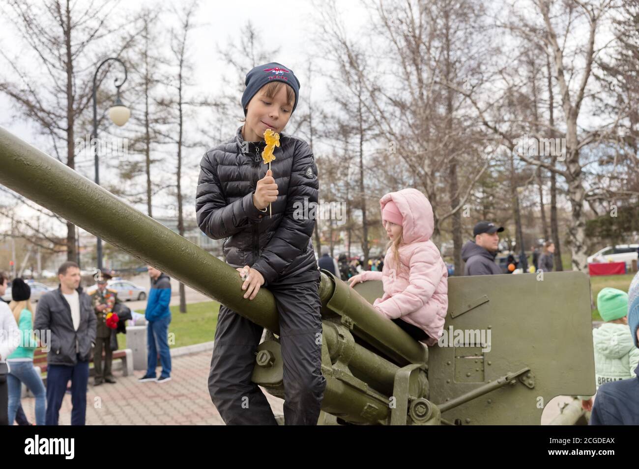 Il ragazzo è seduto sulla pistola di artiglieria antiaerea, che si trova vicino al museo del Victory Memorial durante la celebrazione del giorno della vittoria della seconda guerra mondiale. Foto Stock