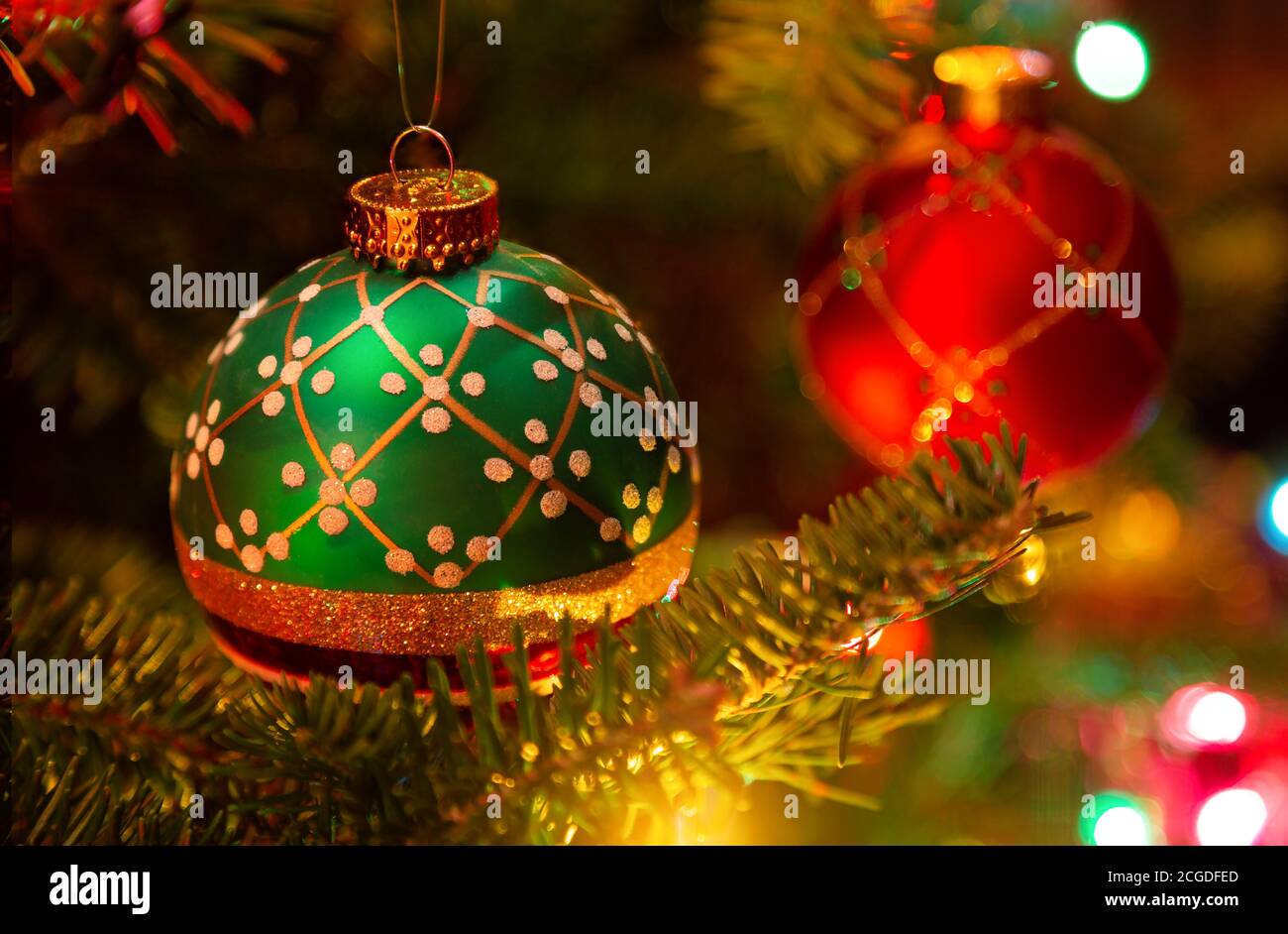 Ornamenti natalizi appesi in un albero di Natale illuminato in abete balsamo. Foto Stock