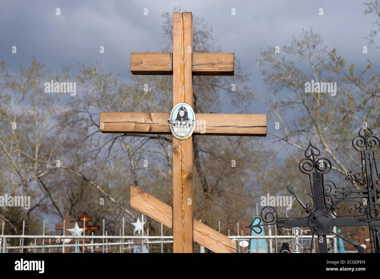 Croce di legno sullo sfondo di alberi di sorgente sul cimitero di Troitsk della città di Krasnoyarsk. Russia. Foto Stock