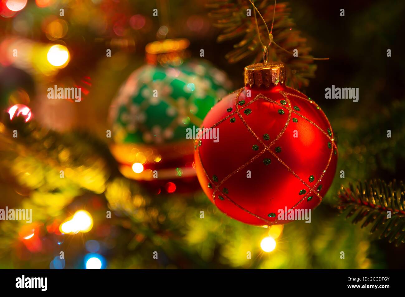 Ornamenti natalizi appesi in un albero di Natale illuminato in abete balsamo. Foto Stock