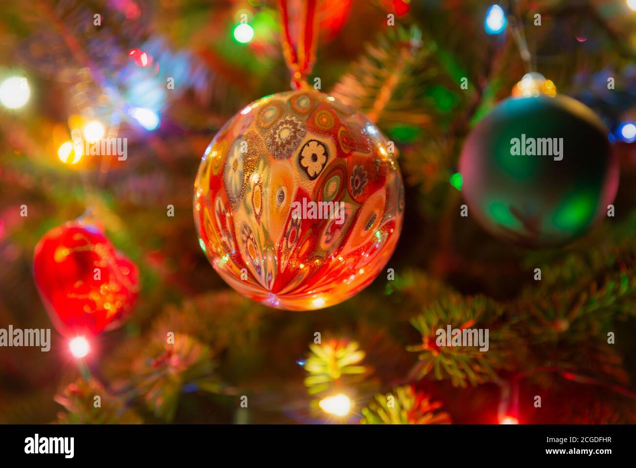 Ornamenti natalizi appesi in un albero di Natale illuminato in abete balsamo. Foto Stock