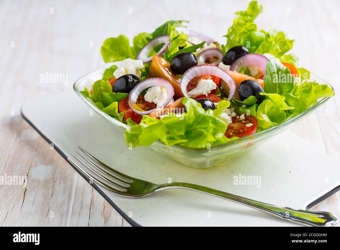 Insalata greca con formaggio feta, olive nere e cipolla su fondo bianco Foto Stock