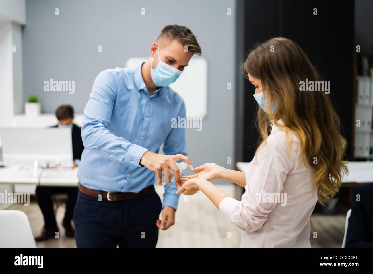 Pulizia delle mani all'ingresso dell'ufficio con igienizzatore antisettico Foto Stock