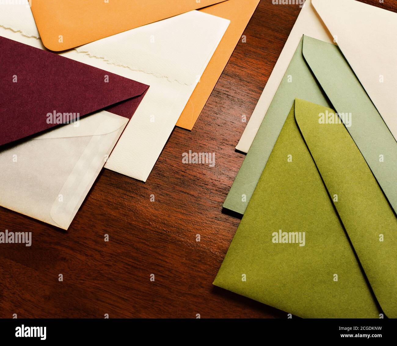 Buste di carta vintage color verde, crema, maroon impilate su legno Foto Stock