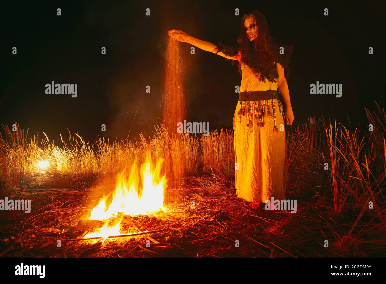 Donna in costume da strega halloween getta le ceneri dei morti. Foto Stock