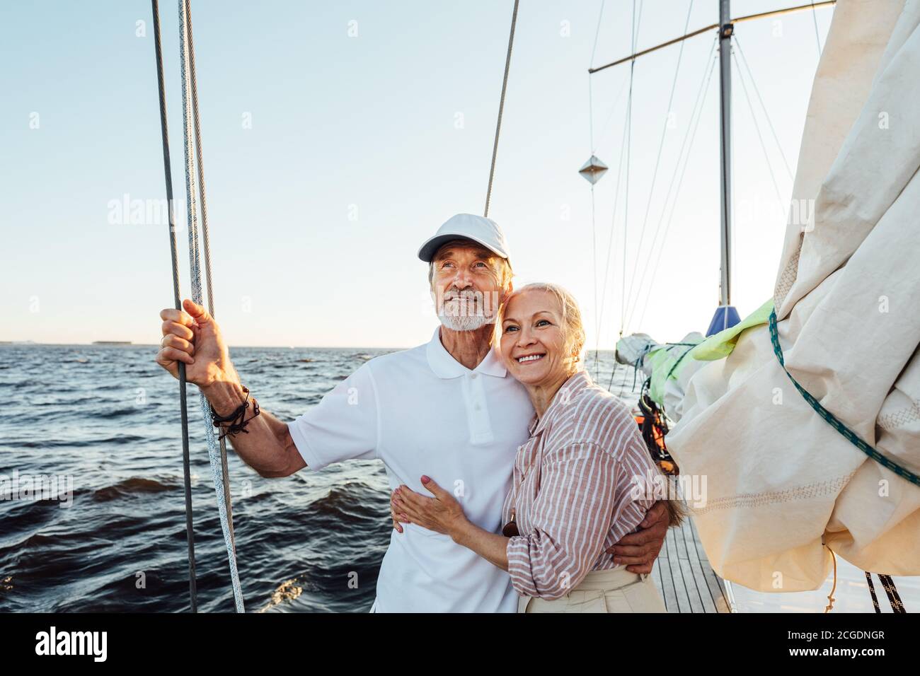 Coppia anziana amorevole che ama godersi la vacanza e guardare a distanza. Coppia matura in piedi insieme e abbracciare su una barca a vela privata. Foto Stock