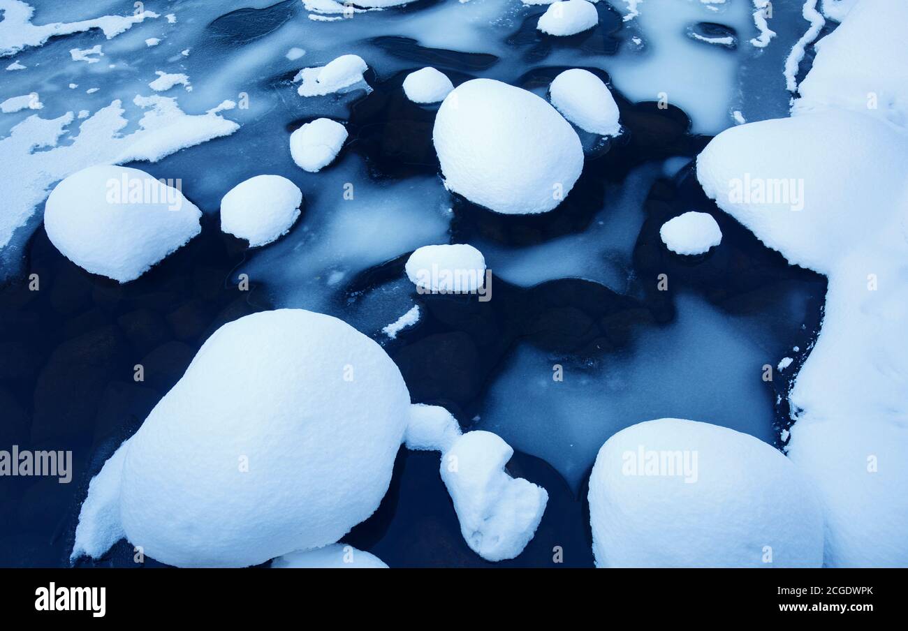 Pietre ricoperte di neve e ghiaccio su un ruscello lento a Winter , Finlandia Foto Stock