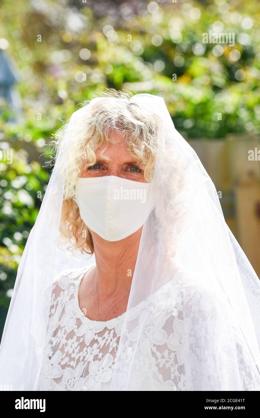 Donna matura femmina che indossa il suo velo di nozze e un volto Maschera durante il coronavirus COOVID-19 pandemia fotografia scattata da Simon Dack Foto Stock
