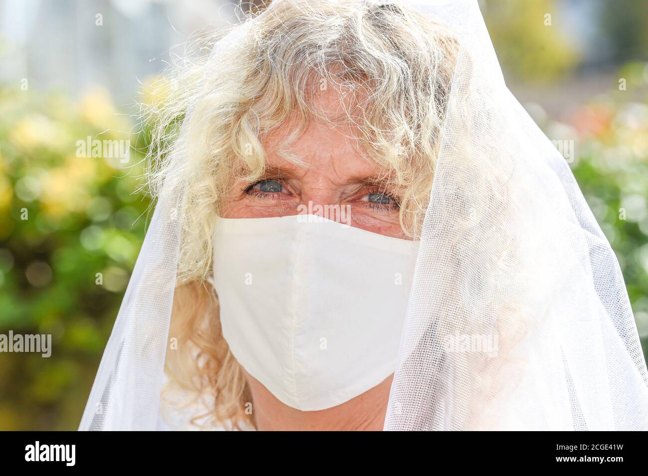 Donna matura femmina che indossa il suo velo di nozze e un volto Maschera durante il coronavirus COOVID-19 pandemia fotografia scattata da Simon Dack Foto Stock