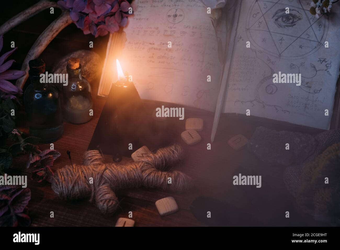 Apri il vecchio libro con incantesimi magici, rune, candela nera ed erbe sulla tavola delle streghe. Concetto occulto, esoterico, divinazione e wicca. Halloween vintage backg Foto Stock