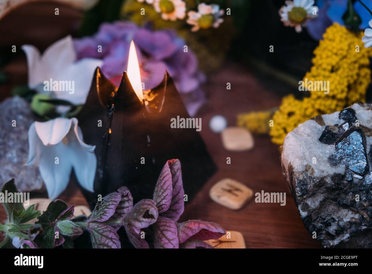 Ancora vita con candela nera bruciante, pietre e sfondo di erbe. Rituale magico nero con simboli occulti, malvagi ed esoterici. Halloween o divinazione Foto Stock