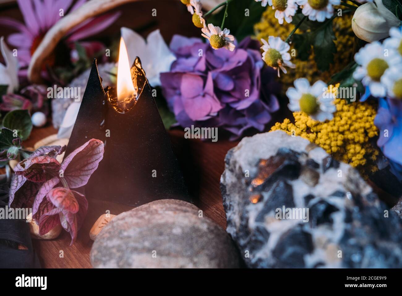 Ancora vita con candela nera bruciante, pietre e sfondo di erbe. Rituale magico nero con simboli occulti, malvagi ed esoterici. Halloween o divinazione Foto Stock