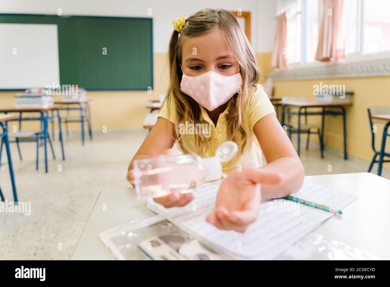 I bambini che mettono gel igienizzante sulle loro mani in classe scolastica. Covid. Foto Stock
