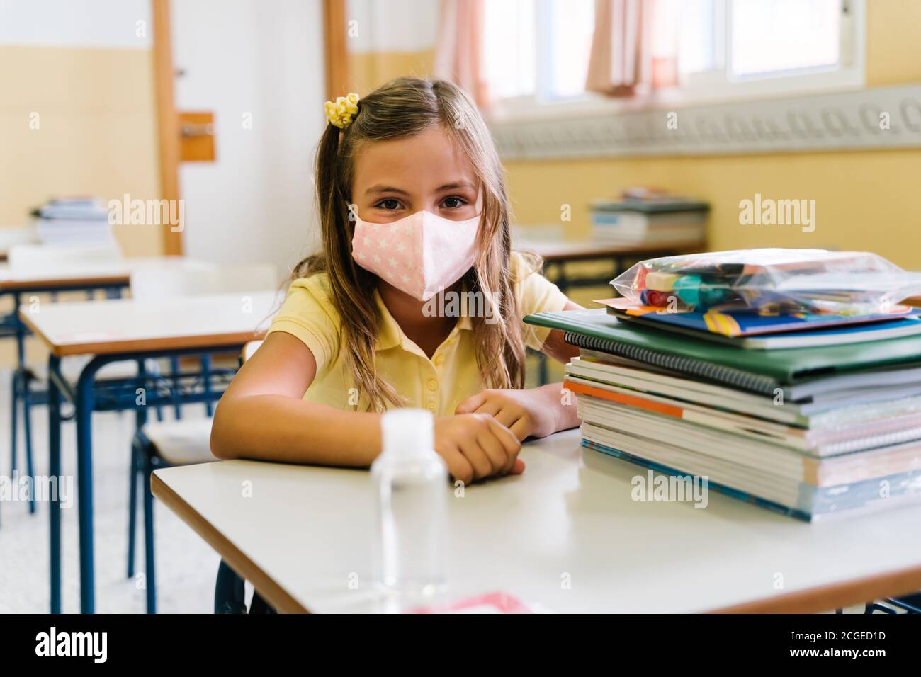 ragazza seduta alla sua sedia in classe indossando una maschera. durante la pandemia coviale Foto Stock