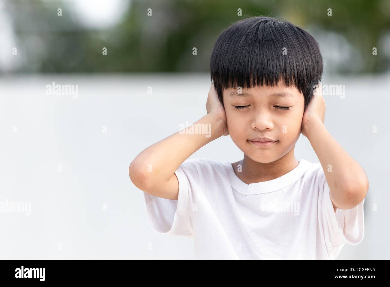 Il bambino asiatico gli coprì l'orecchio. Concetto di violenza familiare domestica. Bambino triste e infelice. Foto Stock