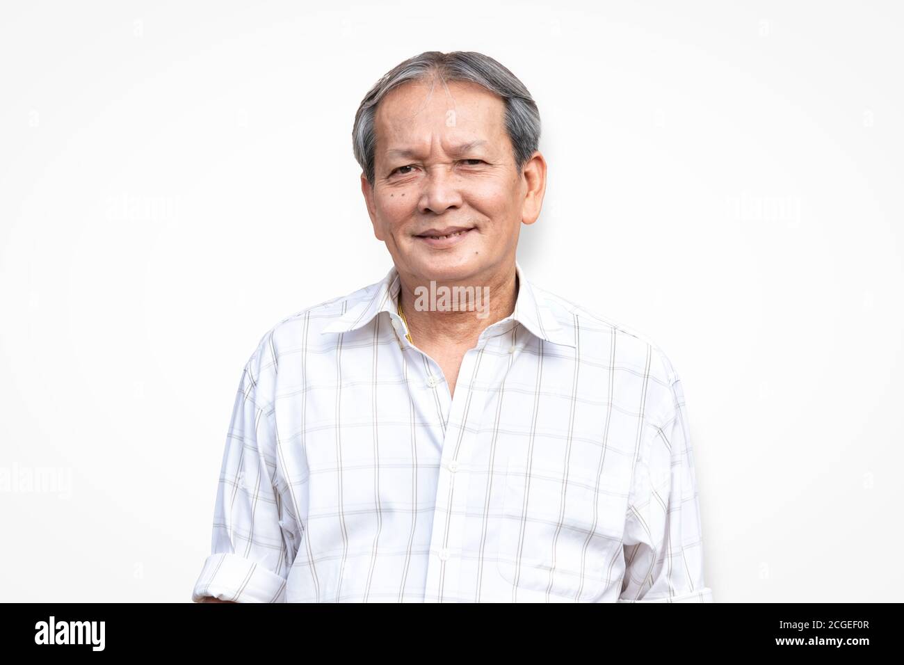 Ritratto di sorridente anziano asiatico in piedi davanti a sfondo bianco con modo sicuro di sé. Primo piano del sorriso più anziano con i capelli grigi. Foto Stock