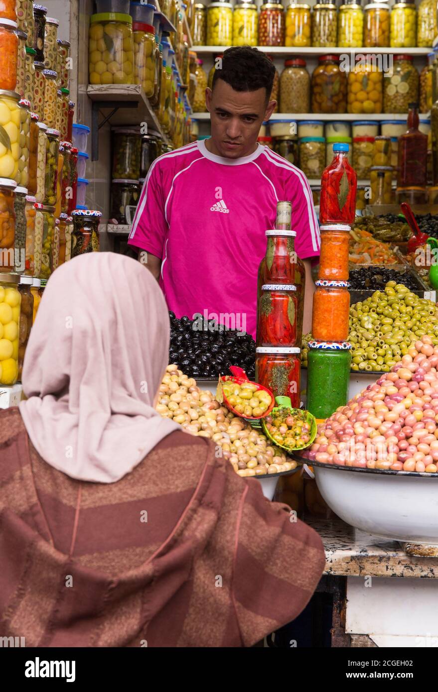 Una donna locale negozi di olive nel souk di Marrakech, Marocco Foto Stock